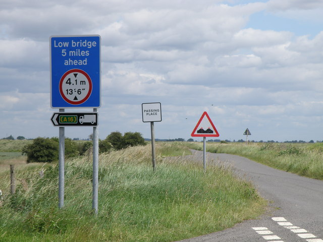 A road sign with a distance marked in imperial units only, but with the height warning in dual units.