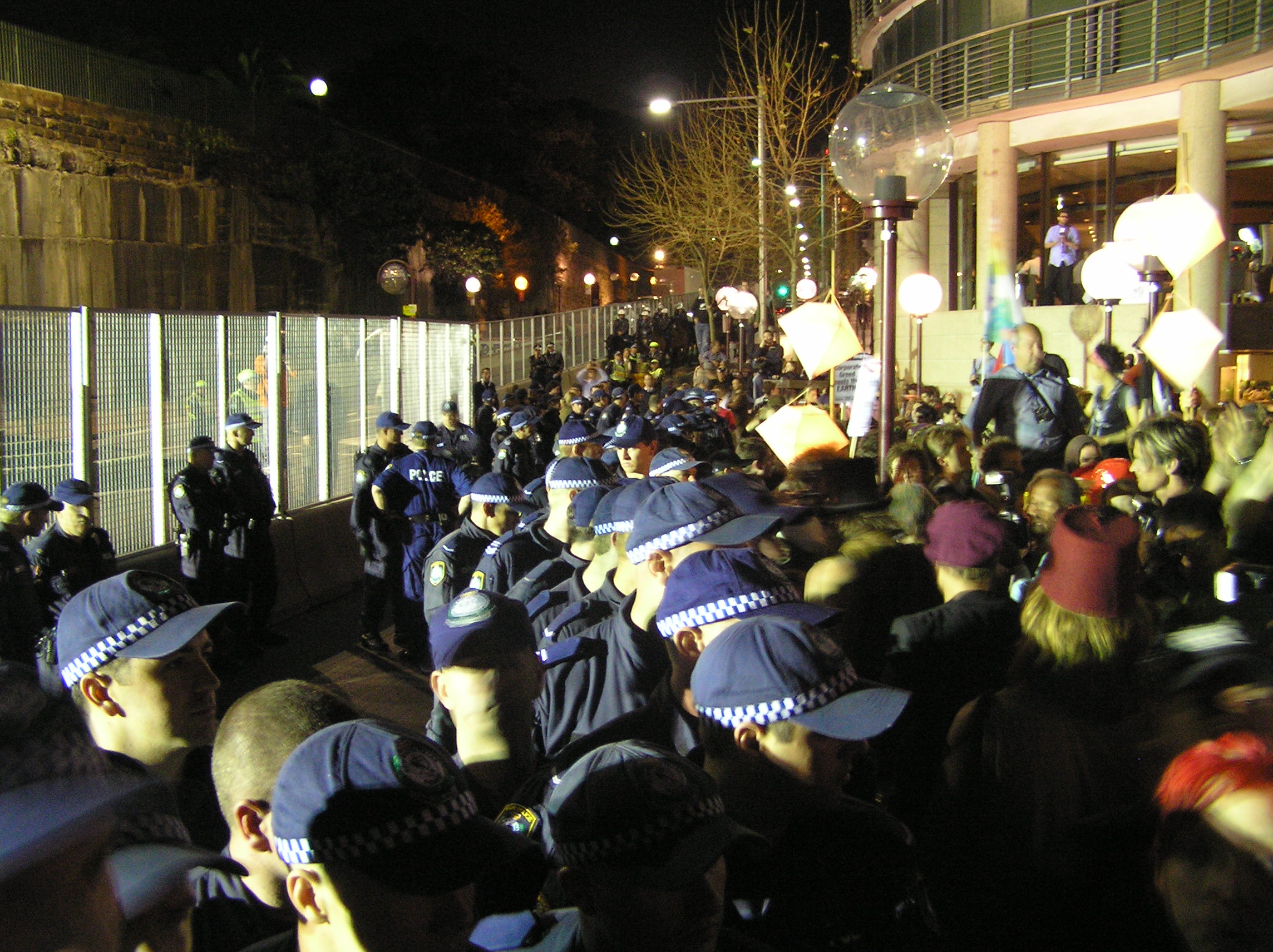 Police line in front of breached section of barricade