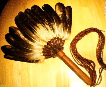 A Warriors (Male) Gourd Dance Eagle Fan. This Gourd Dance Shield Fan is made from immature bald eagle feathers. The handle of this fan was made from the branch of a tree struck by lightning, and the handle of the fan has been stitched, bound, and fringed with buffalo hide.
