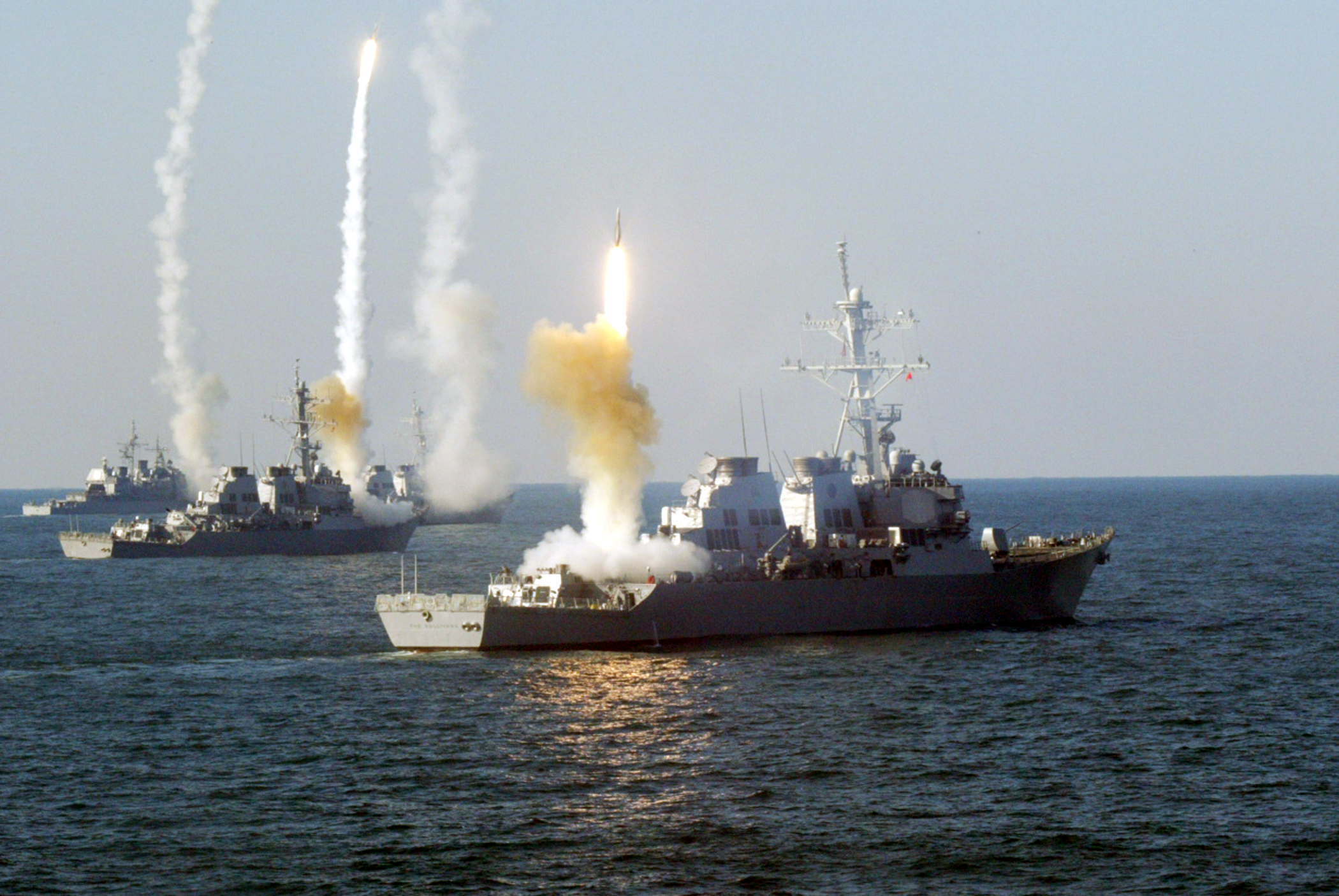 Several U.S. Navy ships firing missiles in a live fire exercise
