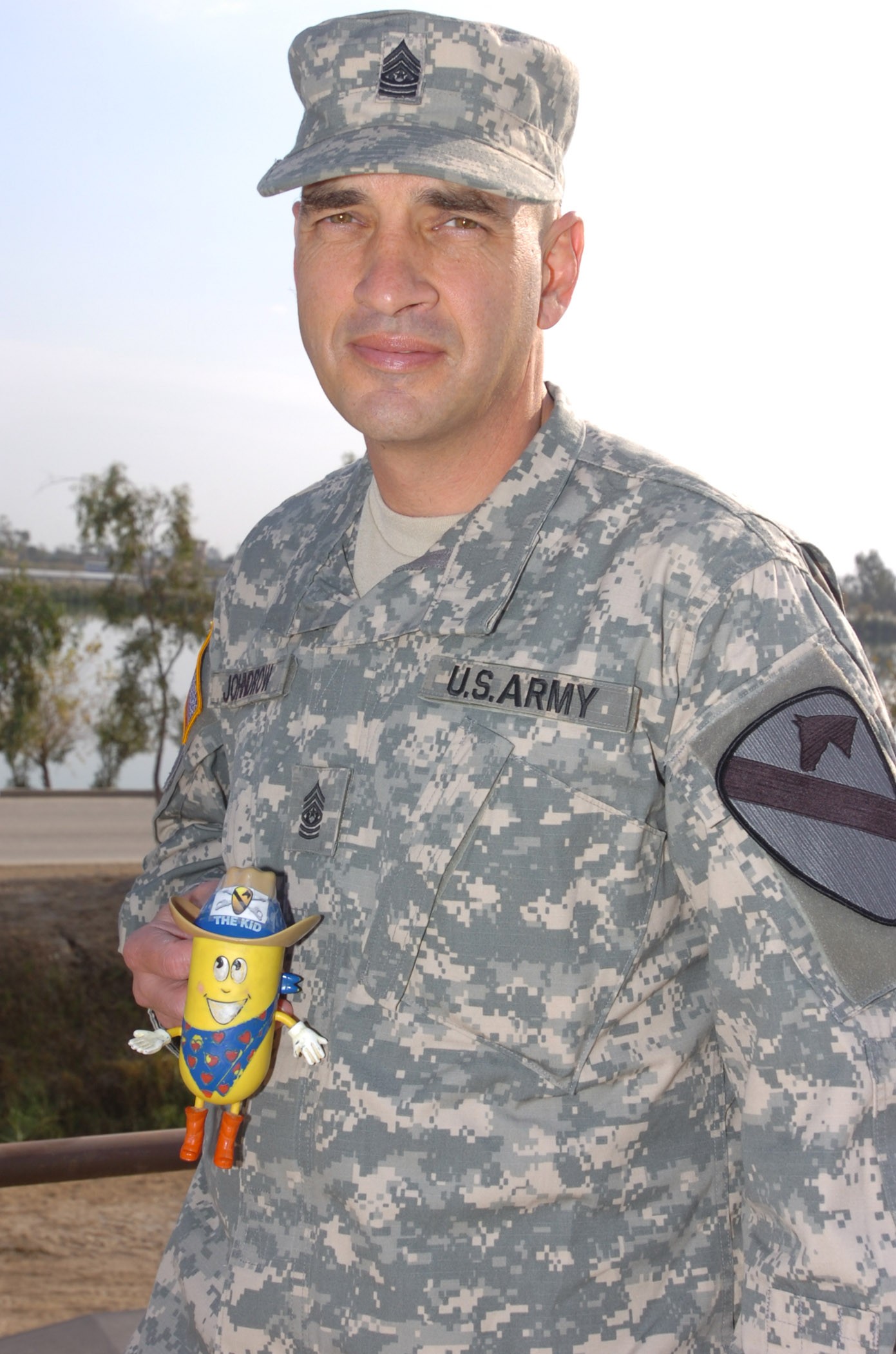 Army Command Sgt. Maj. Philip Johndrow, the senior noncommissioned officer for Multinational Division Baghdad and 1st Cavalry Division, shows off his lucky charm, the “Cav Kid” outside the division headquarters, November 15, 2006. The Cav Kid was given to Johndrow by his wife, Vickie, during the first of his three deployments to Iraq. Johndrow said they have been inseparable ever since.