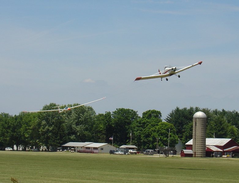 A two place glider on tow behind a Pawnee departing East bound