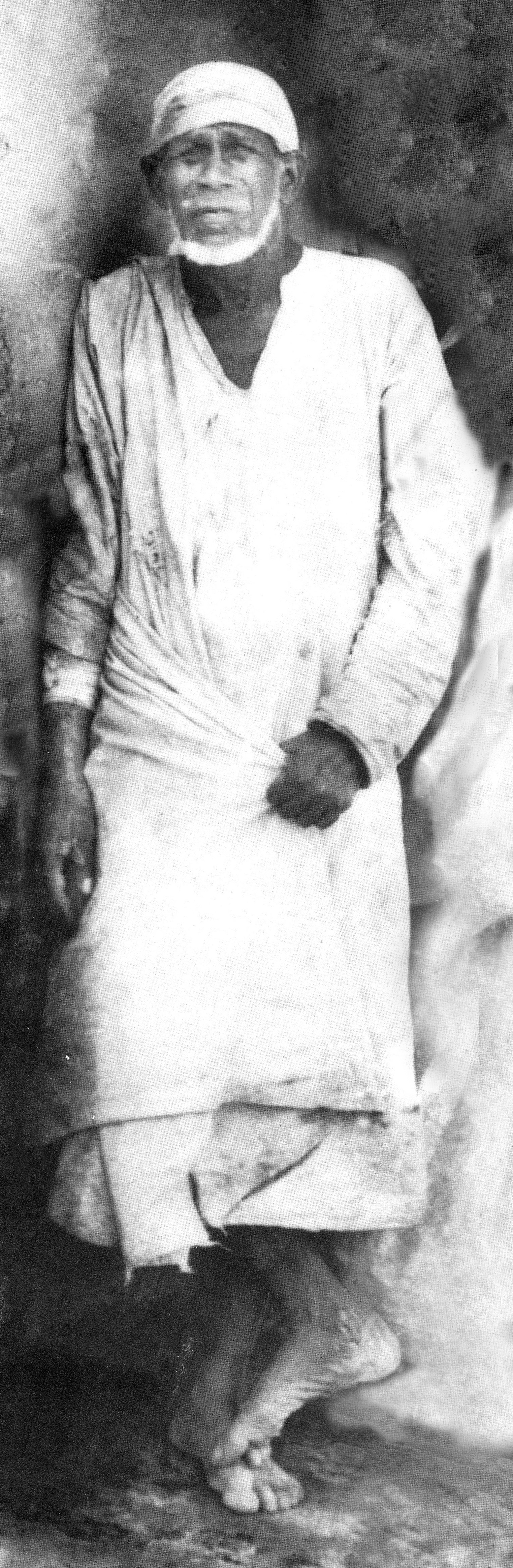 Sai Baba of Shirdi, standing near his mosque
