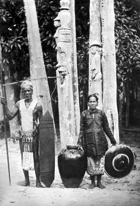The pole carved with a face in the background represents the Raja Entai Nyahu, which is thought to watches over the dead until the tiwah.