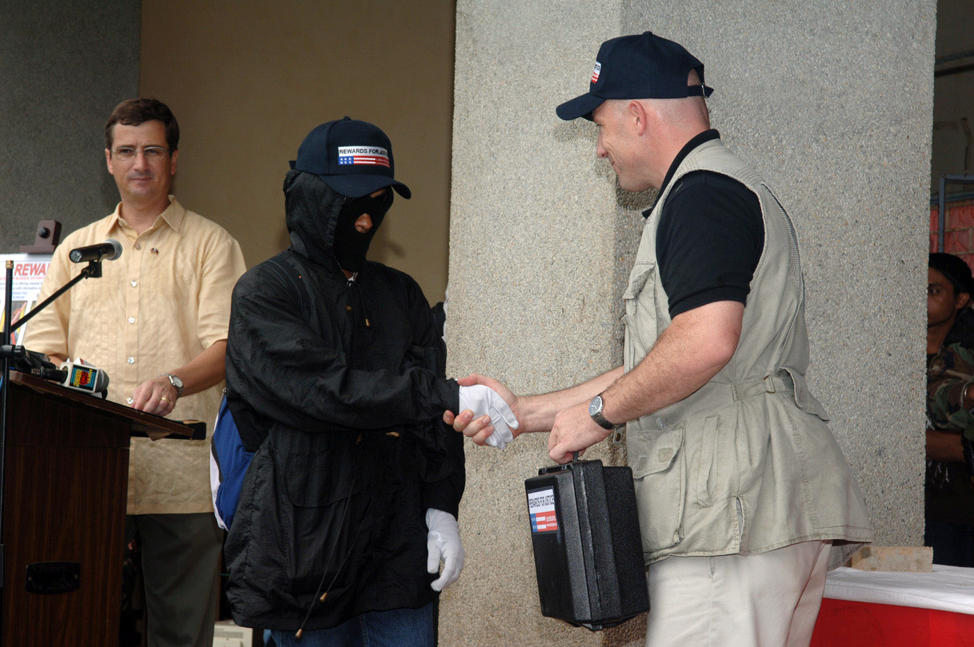 A State Department representative publicly hands over a payment to an informant whose information led to the [...] of Khadaffy Janjalani and Jainal Antel Sali, Jr., leaders of the Filipino militant group Abu Sayyaf.
