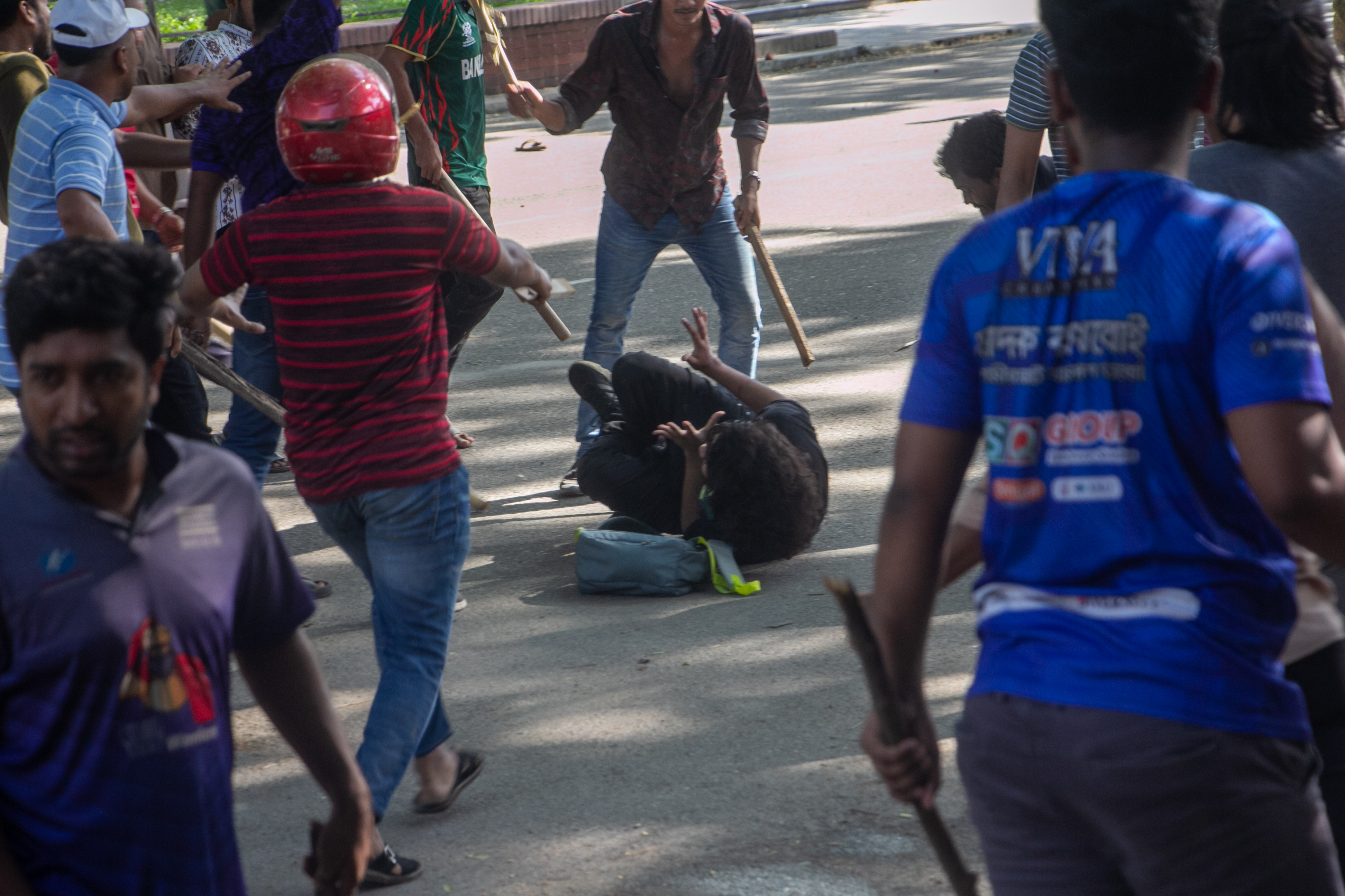 Chhatra League members beating a protester with a baston during a quota reform protest in Dhaka