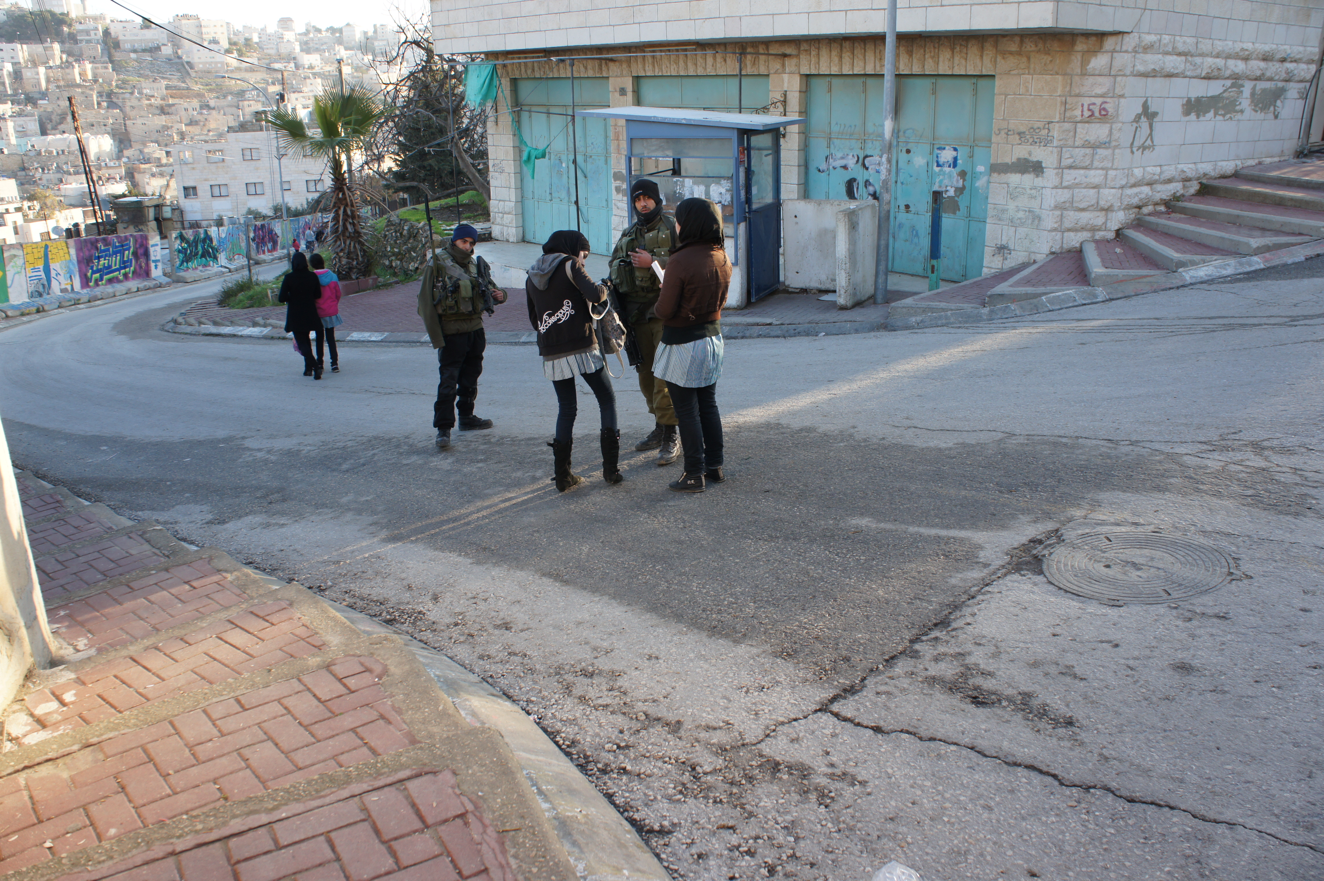 Golani Brigade soldiers and Palestinian schoolgirls at a checkpoint in Tel Rumeida.